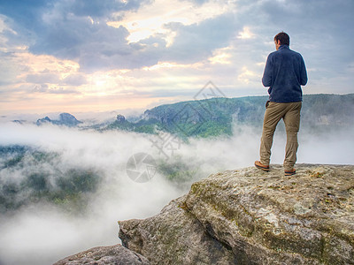 摄影师在山悬悬悬崖上寻找雾 Hiker将拍摄照片日落记录自由艺术家远足探索记者背包男人记忆图片