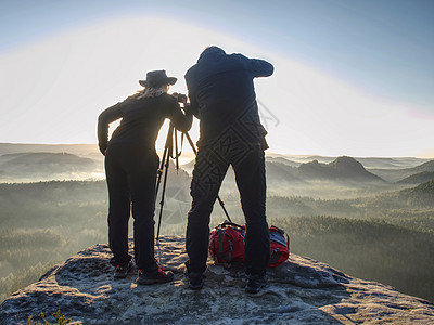 一对夫妇旅游者 在山表日落顶端配有照相摄影机图片