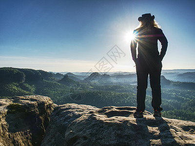 成年奶牛妇女站在一块头顶着头的岩石上山峰冒险天空活动中年男性休闲阳光成人自然公园图片