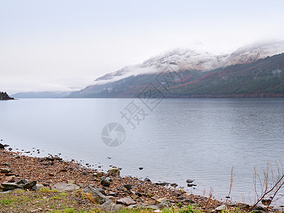 苏格兰希格兰沉暗日落前的山丘湖 在镜水上方有雪色山锥野性河岸海浪石头高地下雨天气树干爬坡季节背景图片