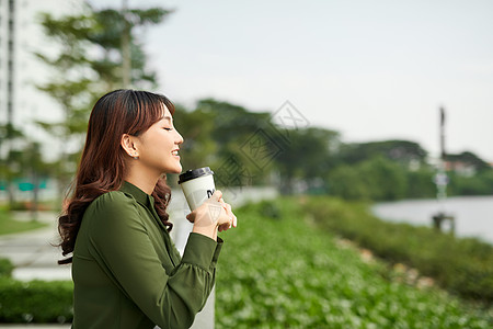 相片中美女在绿公园拿着纸杯和咖啡带外送咖啡图片