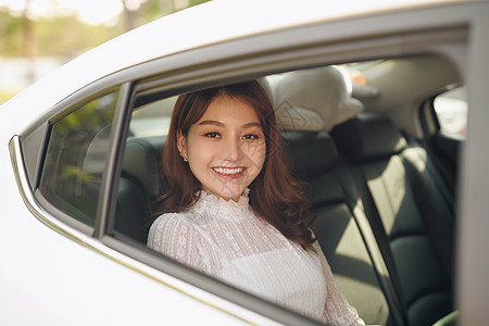 年轻亚洲女性的肖像 透过窗户看镜头 坐在汽车后座上 笑声喜悦运输乐趣快乐旅行女士假期车辆乘客女孩图片