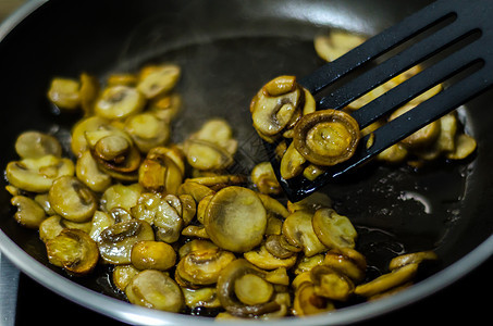切碎的蘑菇煎成黄油 在锅中 素食菜盘油炸营养洋葱草药美食食物平底锅饮食胡椒厨房图片