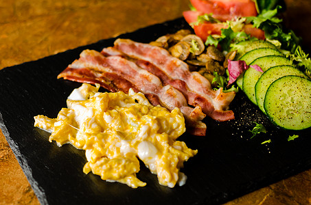 配有培根的炒鸡蛋 配有沙拉 番茄和黄瓜的蘑菇草药食物胡椒黄油脂肪营养育肥早餐烹饪服务图片