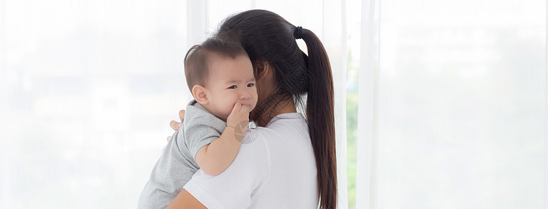 年轻的亚洲母亲抱着小女婴在家里的卧室里一起散步 妈妈带着女儿和照顾 父母和孩子的关系 蹒跚学步的孩子和父母 室内 家庭观念母性新图片