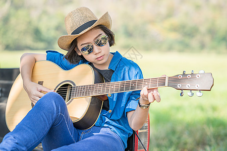 妇女在皮卡上戴帽子和弹吉他草地眼镜吉他太阳镜乐器场地女孩吉他手青少年音乐图片