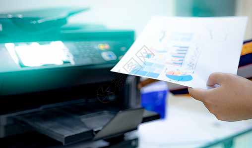 选择性地关注上班族手持纸 多功能激光打印机 办公室内的复印 打印 扫描和传真机 现代印刷技术 复印机 文件和文书工作图片