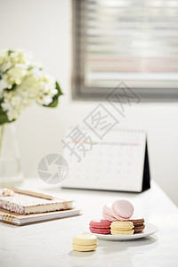 女性办公桌工作空间框架 包括日历 日记 白背景的hortensia花束和macaron 想法 说明或计划写作概念面包桌子陶瓷蛋糕图片