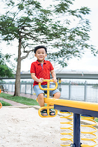 快乐的小男孩在户外的树锯上乐趣幸福喜悦孩子健康公园操场童年跷跷板图片