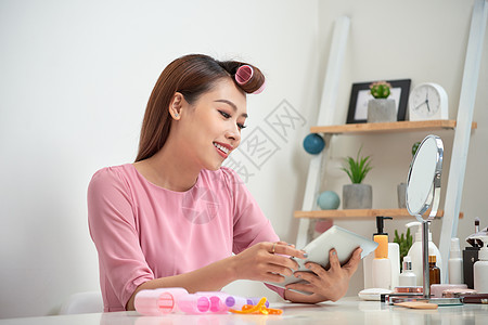 快乐的亚洲女人穿着头发卷发 用平板电脑在家里卷发器金发女郎公寓房子成人微笑闲暇女士女性滚筒图片