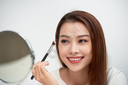 亚洲年轻女子化妆的美丽面孔的特写 亚洲女人正在用刷子在眉毛上涂眼影 漂亮的女孩看着镜子用手做化妆品粉末成人艺术家眼睛白色女性口红图片