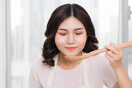 美丽的年轻女子在家里用蔬菜煮汤的肖像 笑声女性厨房黄色女士勺子女孩火炉家庭主妇食物白色图片