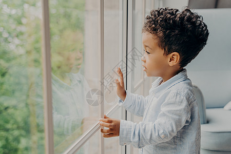 甜美的非裔美国小孩透过窗户看望 等待着父母图片
