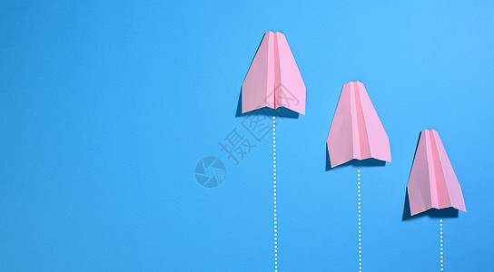 蓝色背景上的三个粉红色纸飞机 独特性和成功的概念 商业中的制胜与竞争图片