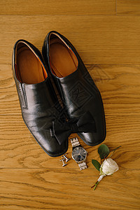黑色男子鞋和领带 在木质纹上 用袖扣 手表和白色玫瑰新郎布顿图片