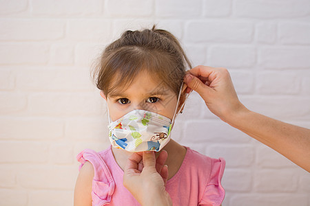 母亲把保护面具贴在她女儿身上婴儿疾病口罩卫生医疗孩子金发女郎女孩白色图片