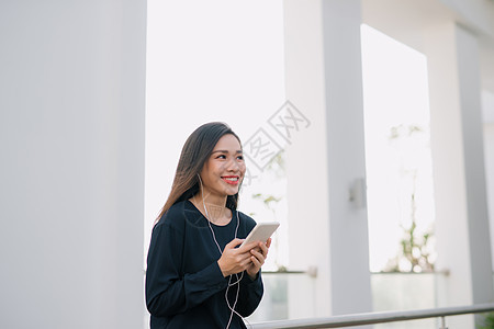 这是我最喜欢的歌 迷人的年轻黑发女孩在夏日露台咖啡厅坐着时 在电话里听音乐 很吸引人女性城市手机语言耳机商业技术讲话音乐快乐图片