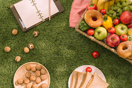 草地上的野餐毯上放着新鲜健康的热带水果 上面放着葡萄 苹果 葡萄柚 橙子和香蕉红色午餐柳条食物果汁早餐白色检查玻璃绿色图片