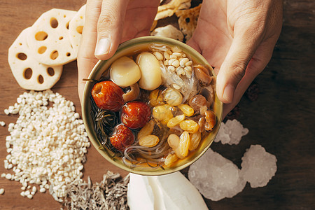 手牵着碗中的清宝梁美食食物勺子糖浆白色绿色红色桂圆甜点木头图片