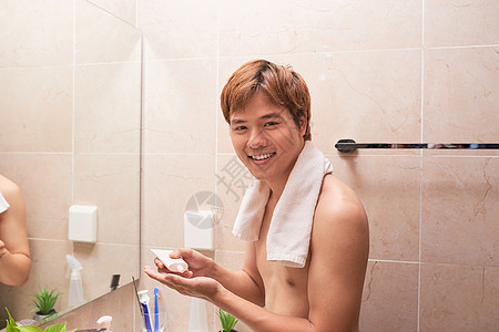年轻英俊的亚洲男子 在浴室当面施奶油图片