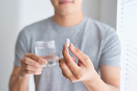 欢乐的亚洲人拿着药片和一杯水 看着摄影机胶囊男性治疗疾病药品医疗药店成人流感图片