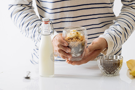 以酸奶 坚果 香蕉和芝麻种子提供健康的早餐 一碗新鲜水果饮食勺子燕麦黄色甜点白色食谱玻璃食物图片