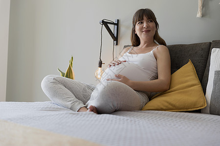 在床上休息的孕妇父母卧室闲暇婴儿肚子微笑腹部母性女性女士图片