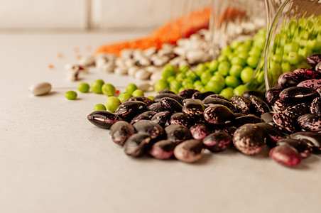 一组不同的干豆类放在玻璃杯中 有点散落 红扁豆 绿豌豆 红豆 白豆 选择性关注红豆大豆拼贴画营养种子蔬菜食物收藏粮食背景图片