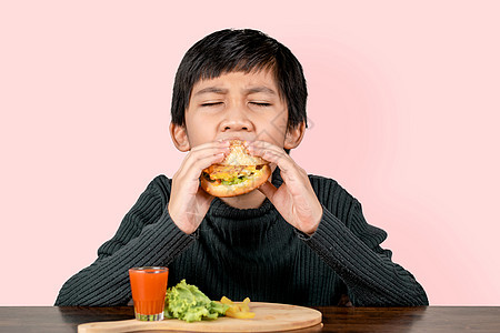 可爱的亚洲男孩 吃一个美味的汉堡包和幸福快乐孩子们饮食享受孩子青少年午餐垃圾食物男性小吃图片