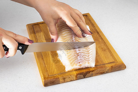 女性手在切肉板上用刀割鱼肉厨房鱼片白鱼烹饪女士海鲜食物餐厅木板养分图片