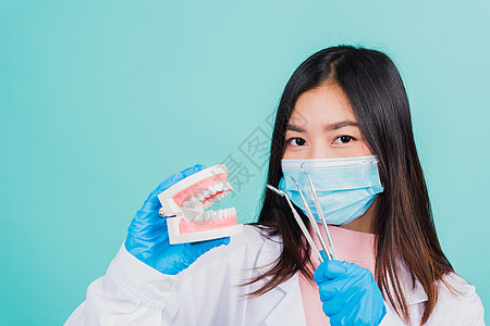 拿着专业工具和模型牙假牙的妇女牙医矫正治疗手术保健蓝色乐器口腔科医生微笑病人图片