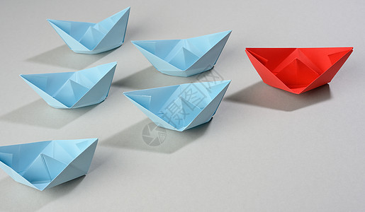 灰色背景的纸船小组 一个团队中强力领导的概念 操纵群众 一折纸经理团体老板血管折叠竞赛蓝色玩具舰队图片