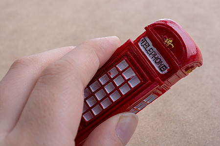手握红色电话亭盒子公用电话城市电话英语图片