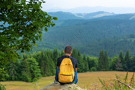 一个人坐在悬崖上享受和平的绿色山地景色 心平气和 放松石头男性森林高度自由背包旅行远足者顶峰旅游图片