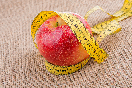 红色苹果 上面有测量磁带厘米营养尺寸成功水果仪表饮食数字重量药品图片