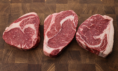 剪切板上三块生牛排牛排观点美食牛扒厨师食物木头端粒高角度屠夫木板图片