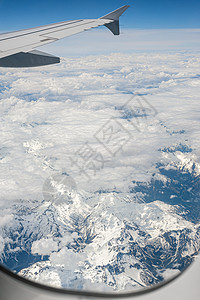 空中飞机在云层天空和阿尔卑斯山脉的窗口中看到高空雪覆盖山峰 笑声航班空间天气顶峰旅行翅膀地面运输蓝天飞机图片