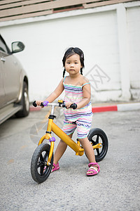 小女孩在停车场学骑平衡的自行车来玩图片