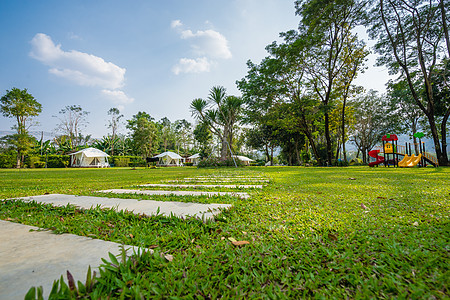 绿草坪和花园帐篷的步行道路操场旅行派对草地冒险蓝色爬坡天空树木闲暇图片