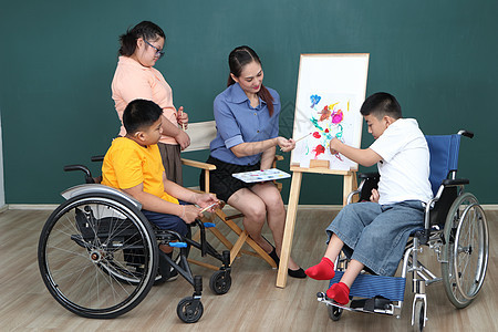 一组残疾和自闭症的年轻女孩正在通过用水绘画和油漆来训练她们的手和手指肌肉 a 教育画家幼儿园喜悦幸福学校男生乐趣童年快乐孩子们图片