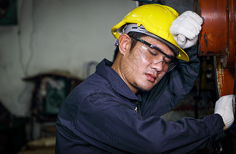 亚洲男性工人穿着制服 戴头盔和安全眼镜 打个盹图片