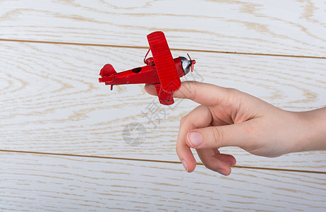 手持玩具飞机在木质纹理上世界商业航班运输乘客车辆旅行白色喷射航空公司背景图片