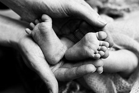 孩子们的脚在白色的母亲和父亲的手上 母亲 父亲和刚出生的孩子 快乐家庭人的概念 黑与白家庭压痛护理妈妈新生产妇赤脚婴儿皮肤投标图片