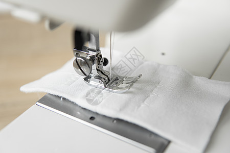 在木制桌子上贴着白布的缝纫机女裁缝棉布针线活裁缝物品时尚工作职业商业工具图片