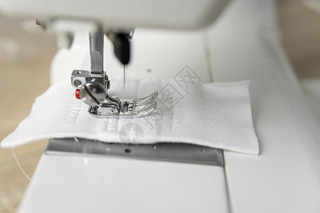 在木制桌子上贴着白布的缝纫机职业机器商业物品针线活女裁缝工厂接缝材料棉布图片
