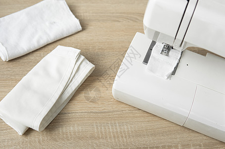 在木制桌子上贴着白布的缝纫机工作作坊工厂工艺纺织品衣服职业接缝材料针线活图片