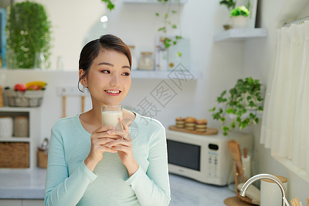 饥渴的年轻女子在厨房喝杯子里的牛奶图片
