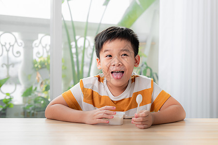 可爱的小男孩在家里吃冰淇淋早餐饮食白色小吃食物孩子幸福奶制品童年勺子图片