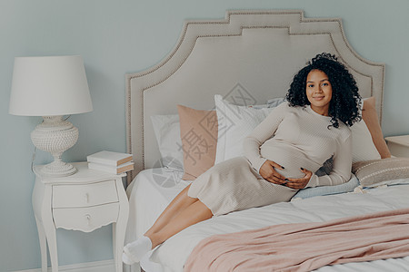 在家床上放松和抚摸肚子的快乐 可爱的怀孕女孕妇图片