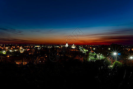 日落背景下的城市夜景 蓝栗色的天空 黎明时分 红色天空中的地平线 城市的全景 夜间的天空线 夜间街道与地平线图片